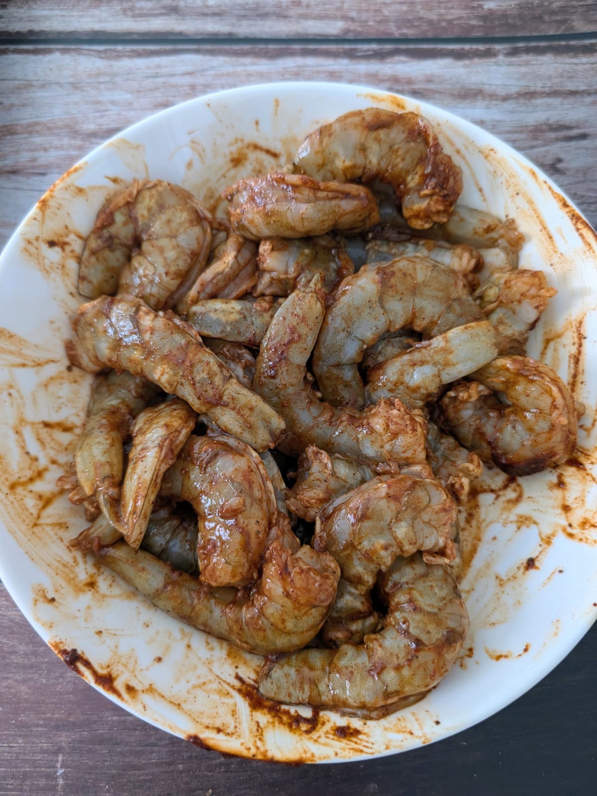 seasoned raw shrimp in a white mixing bowl.