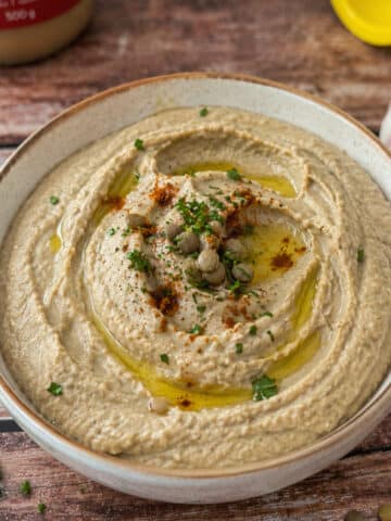 creamy lentil dip with tahini in a bowl garnished with paprika and parsley.