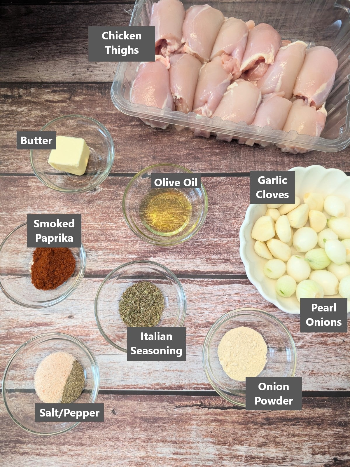 Ingredients needed for easy oven baked chicken thighs including chicken thighs, garlic, pearl onions, butter, and seasonings.