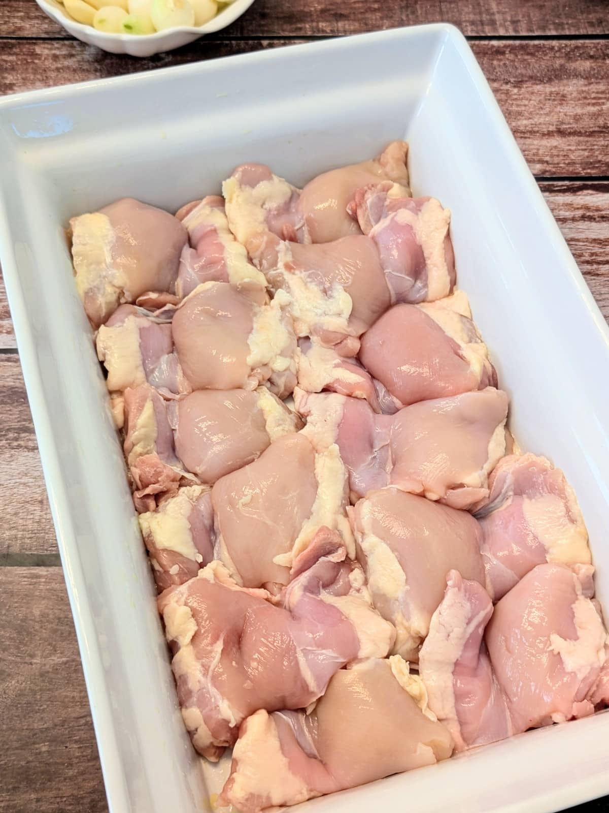 Boneless skinless chicken thighs arranged in a baking dish before seasoning.