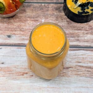 Creamy roasted red pepper Greek yogurt sauce in a glass jar.