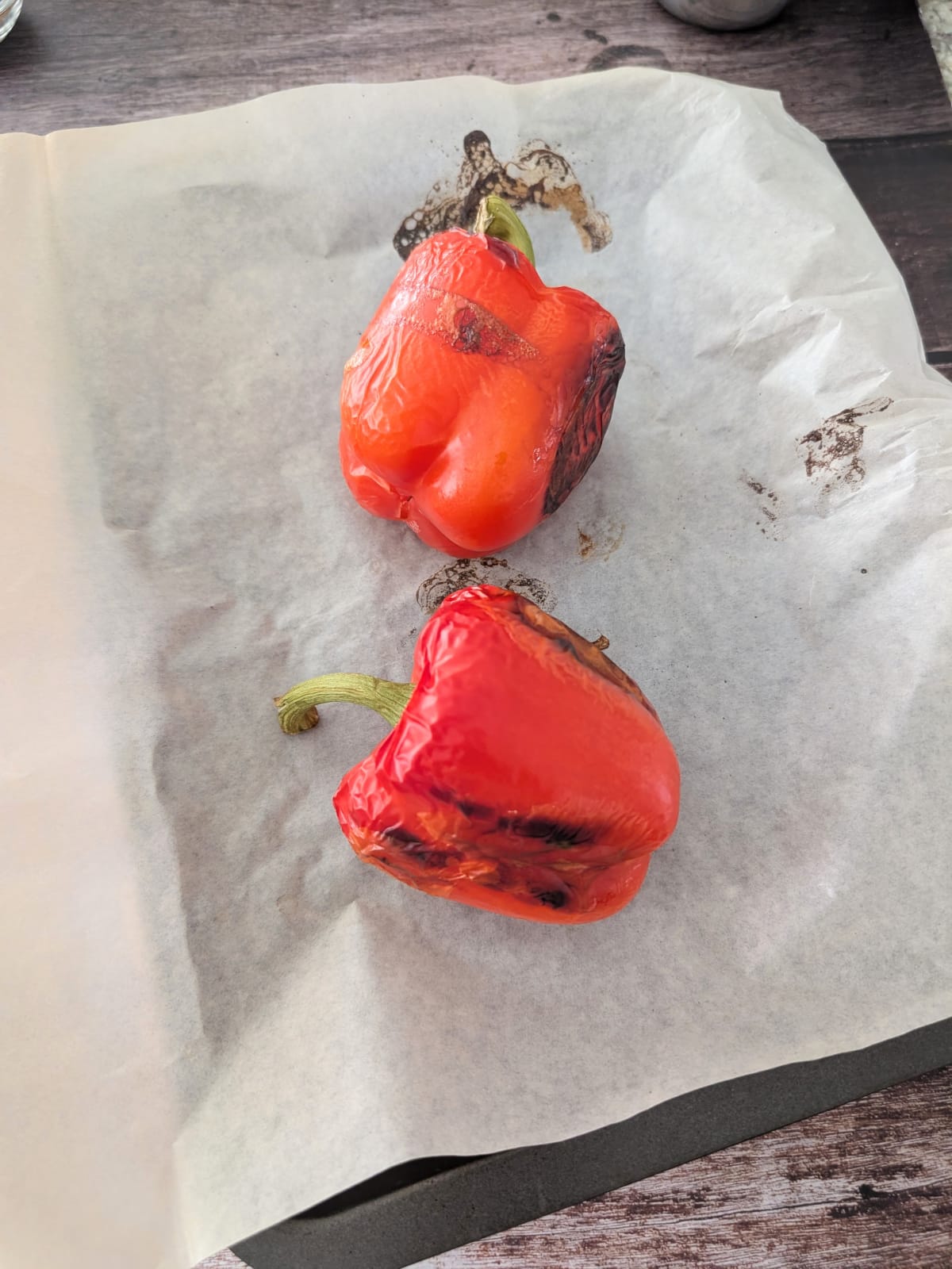 roasted red peppers on a parchment paper lined baking dish.