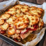 Serving of baked chicken with roasted red peppers, sweet potatoes and melted mozzarella lifted from the sheet pan.