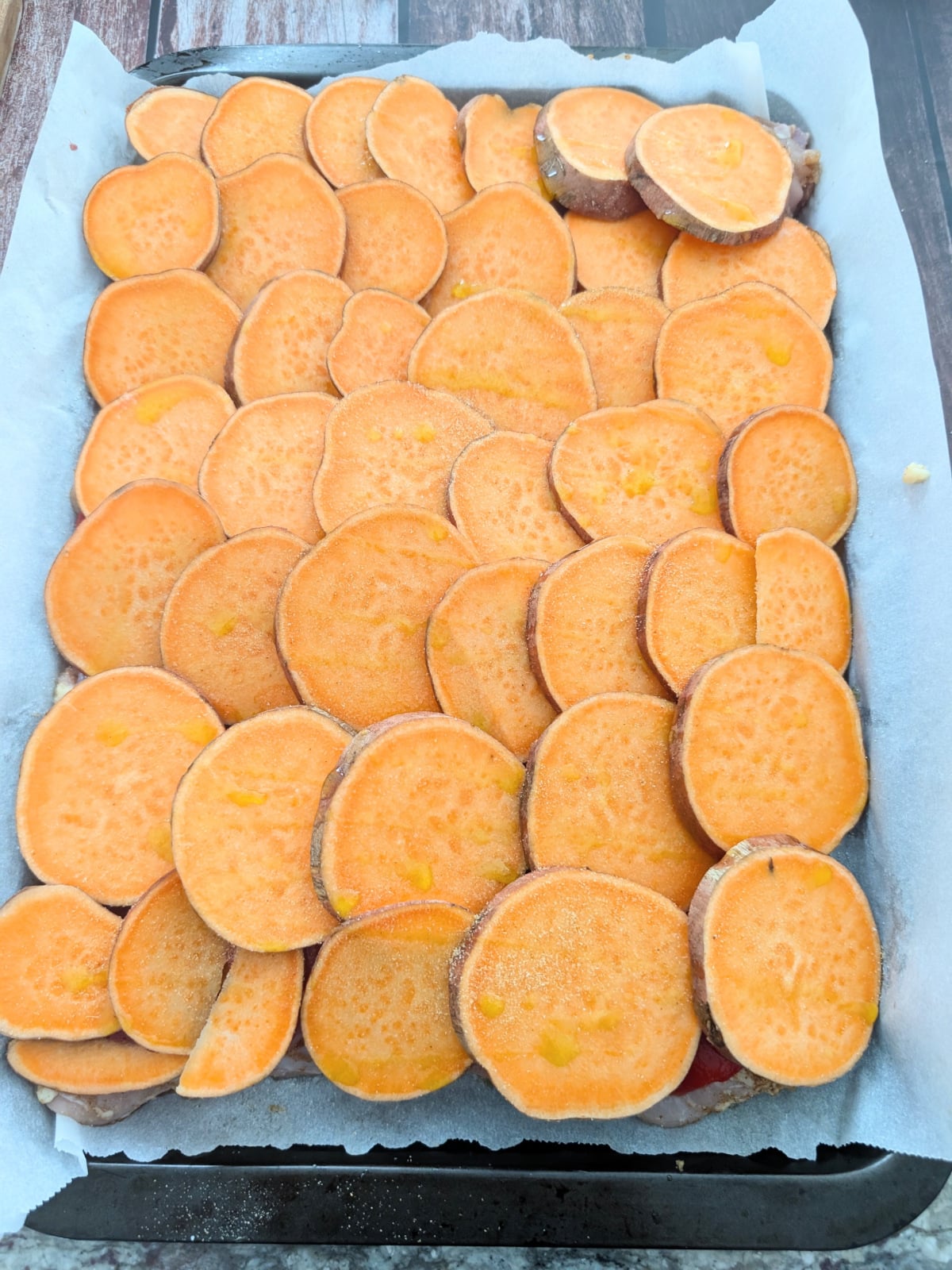 Thinly sliced sweet potatoes layered over roasted red peppers and chicken thighs.