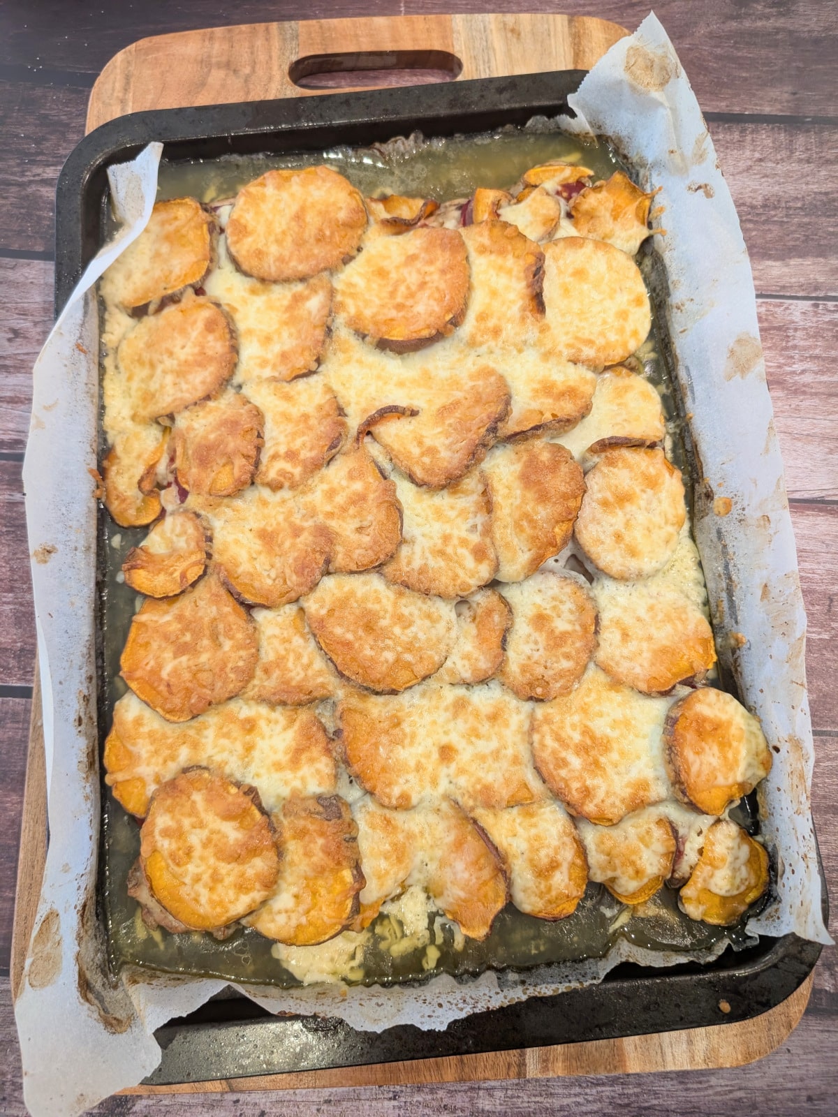 Baked chicken thighs with roasted red peppers, sweet potatoes and melted mozzarella on a sheet pan.