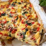 Easy breakfast strata with bread, eggs, ham, mushrooms, spinach, red peppers and melted cheese in a baking dish.