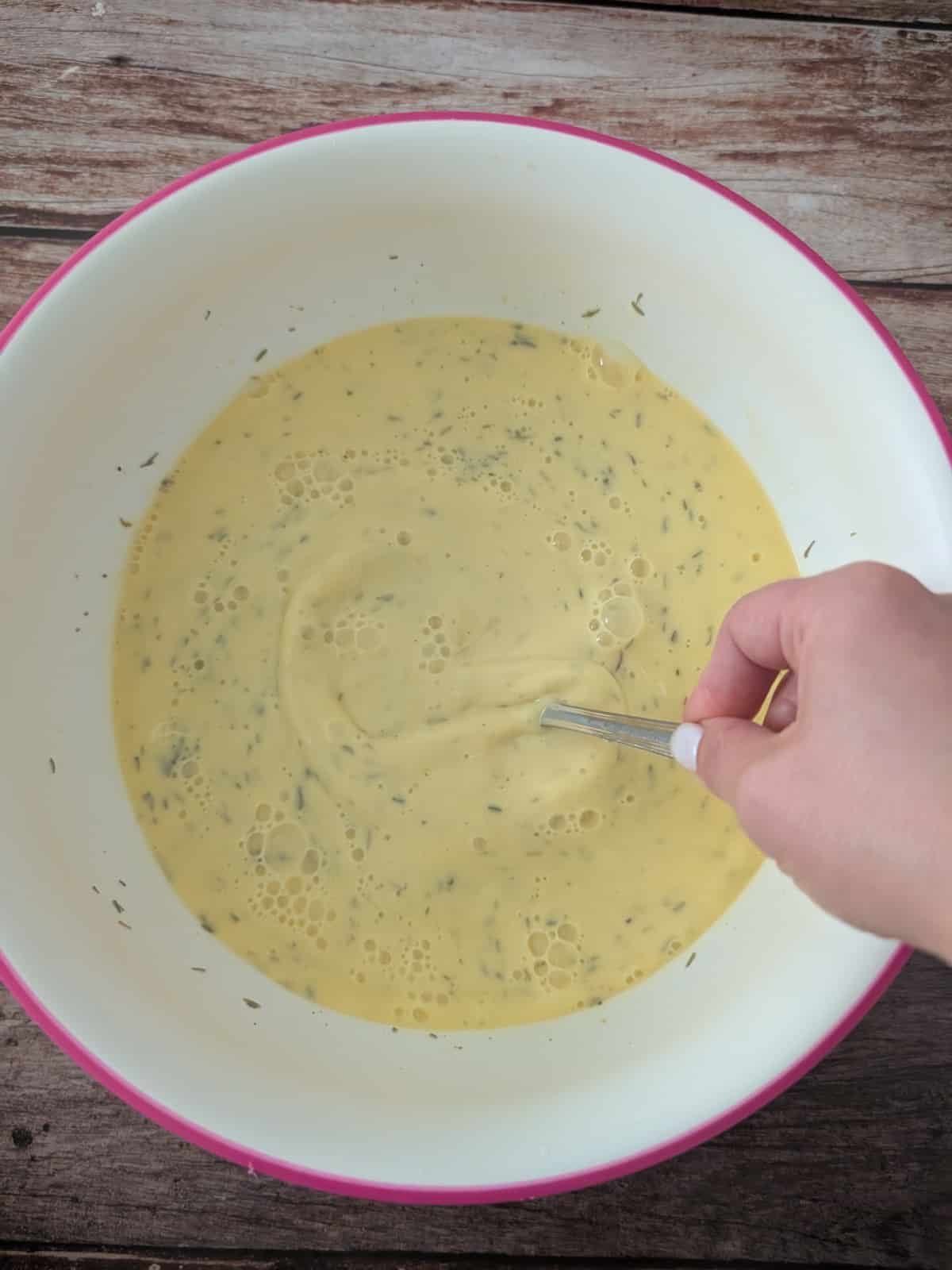 Eggs whisked with milk and seasonings for breakfast strata custard.